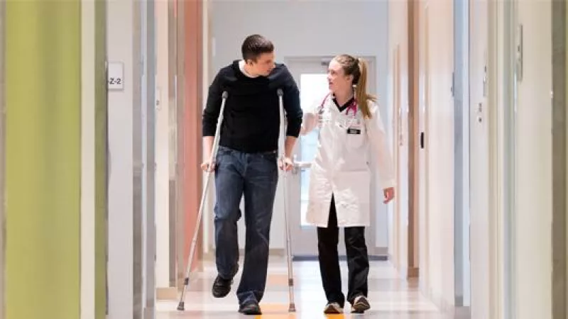 UI Health Care provider Tiffany Sorensen walks with a patient down a hallway at the Scott Blvd. Urgent Care location